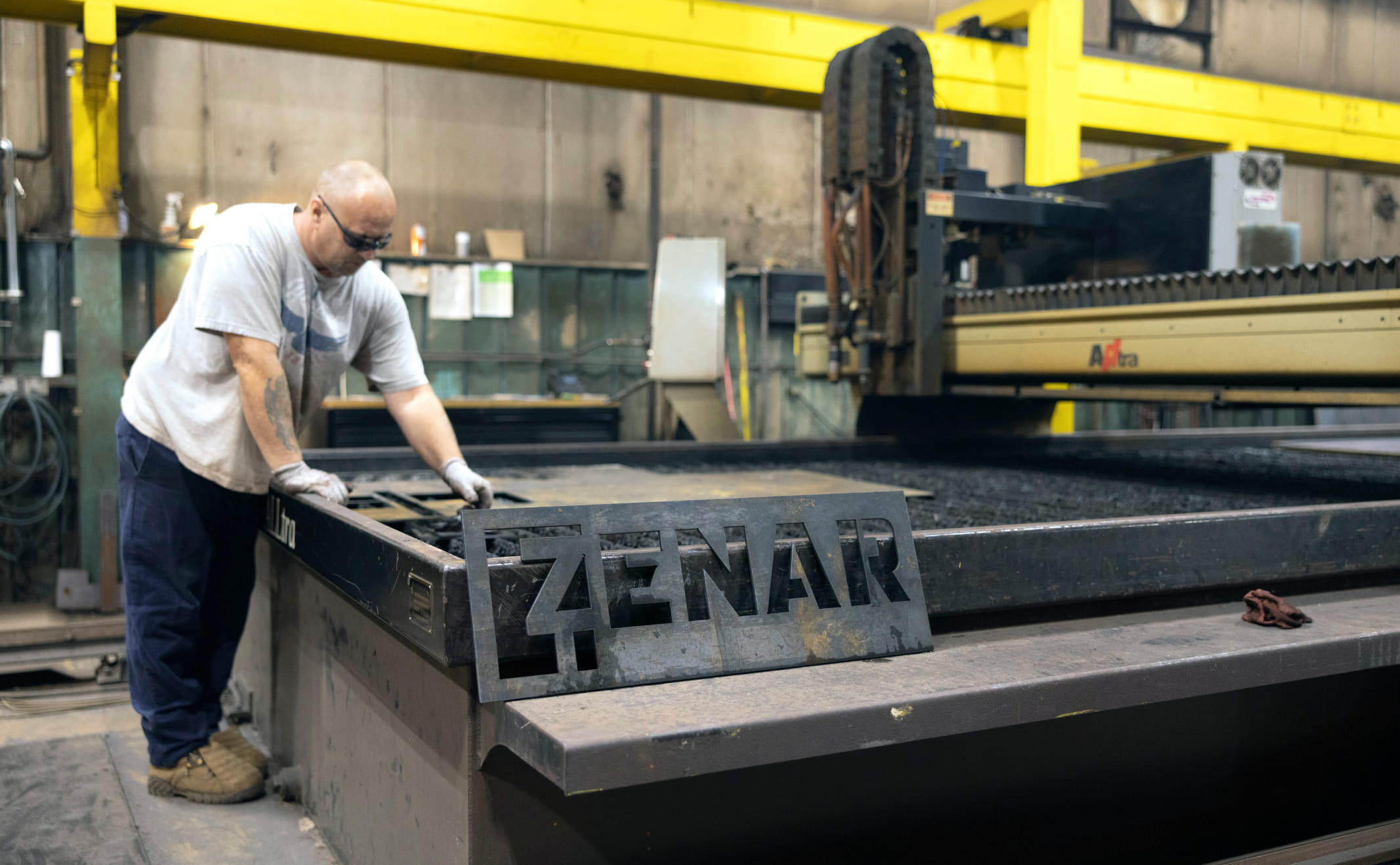 Worker cutting sheet metal with Zenar Crane logo